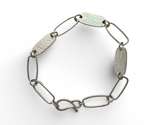 Silver bracelet with textured links on a white background