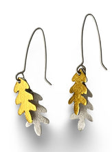 Load image into Gallery viewer, Pair of earrings with gold and silver leaf designs on a white background
